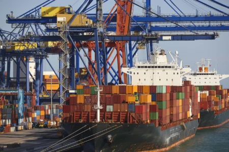 Container ships docked at a port, showcasing HS Agency's logistical solutions and expertise in transportation, shipping, and warehousing services. The image highlights the bustling activity of the shipping industry, reflecting HS Agency's commitment to efficient and reliable logistics across the U.K and Ireland.