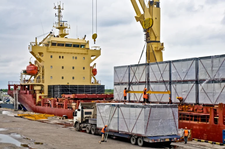 Workers unloading cargo from a ship at a port, showcasing HS Agency's logistical solutions and commitment to efficient shipping and transportation services. The image highlights the integration of warehousing and delivery processes, reflecting the company's dedication to managing complex supply chains across the UK and Ireland.